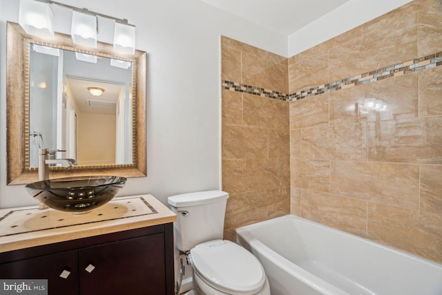 full bathroom featuring tiled shower / bath combo, vanity, and toilet