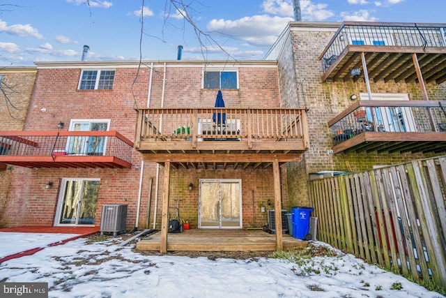 snow covered back of property featuring a balcony and central AC