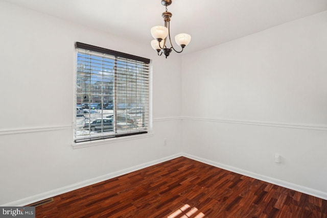 unfurnished room with dark hardwood / wood-style floors and a notable chandelier