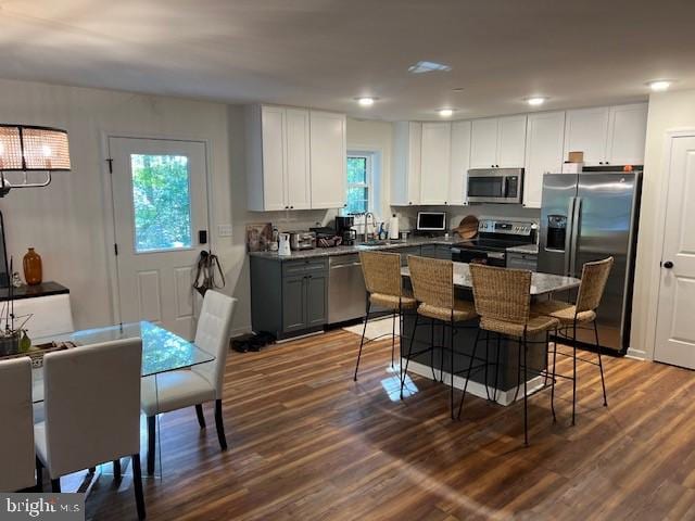 kitchen featuring a kitchen breakfast bar, gray cabinets, white cabinetry, and appliances with stainless steel finishes