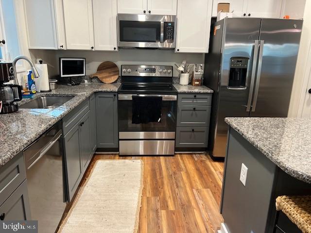 kitchen with light hardwood / wood-style floors, white cabinets, sink, stainless steel appliances, and gray cabinets