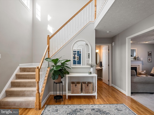 stairway featuring a high ceiling, a textured ceiling, and wood-type flooring