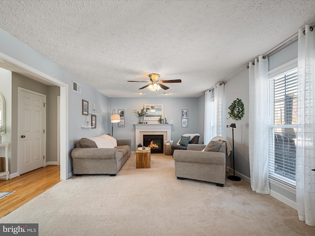 living room featuring light colored carpet, a textured ceiling, and ceiling fan