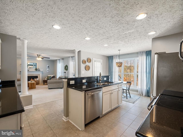 kitchen with ornate columns, appliances with stainless steel finishes, light carpet, sink, and pendant lighting