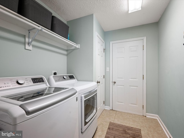 clothes washing area featuring a textured ceiling, light tile patterned floors, and washing machine and clothes dryer