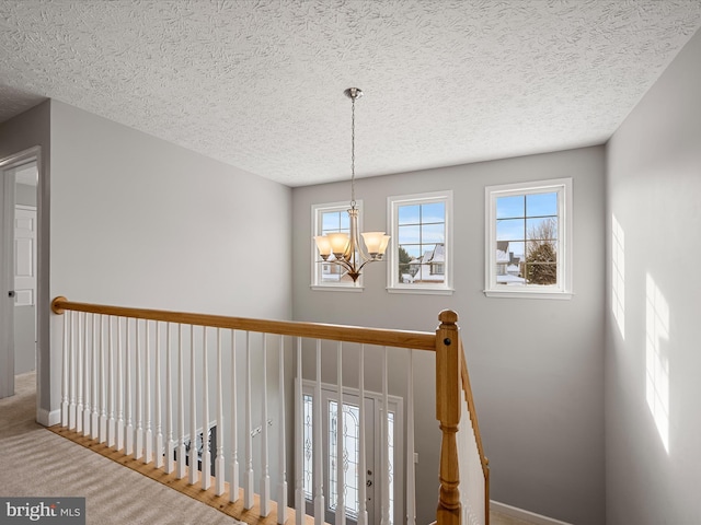 staircase with a notable chandelier, a textured ceiling, and carpet floors