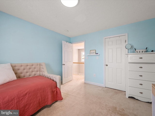 bedroom featuring light colored carpet and a textured ceiling