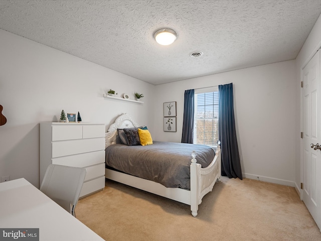 bedroom featuring light carpet and a textured ceiling