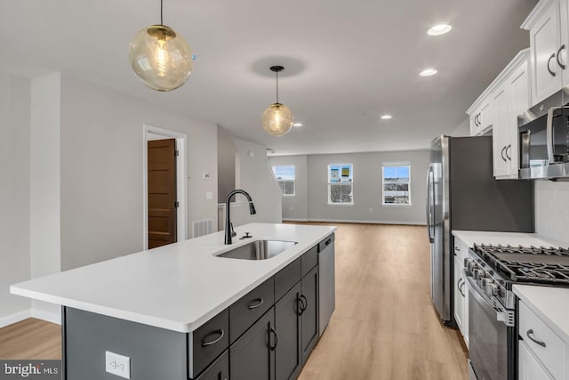 kitchen featuring decorative light fixtures, sink, white cabinetry, and appliances with stainless steel finishes