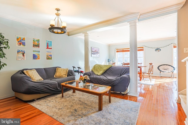 living room featuring a notable chandelier, crown molding, decorative columns, and hardwood / wood-style flooring