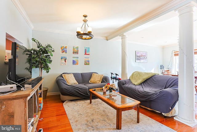 living room featuring decorative columns, crown molding, hardwood / wood-style floors, and a chandelier