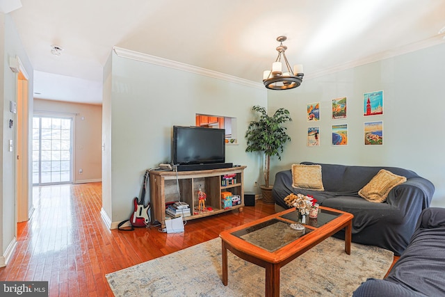 living room featuring an inviting chandelier, hardwood / wood-style floors, and crown molding