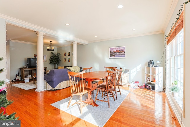 dining area featuring crown molding, decorative columns, and hardwood / wood-style floors