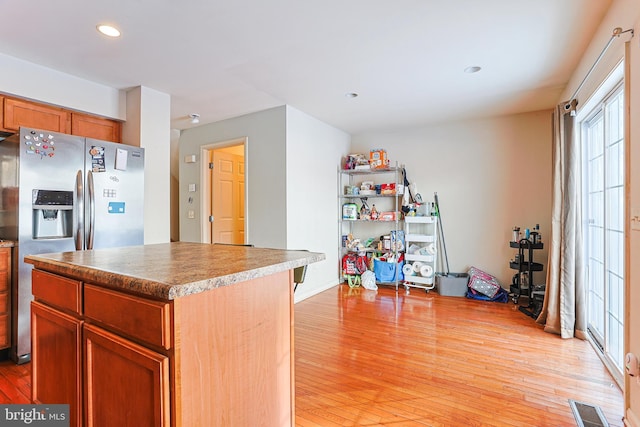 kitchen featuring stainless steel fridge with ice dispenser, light hardwood / wood-style flooring, and a center island