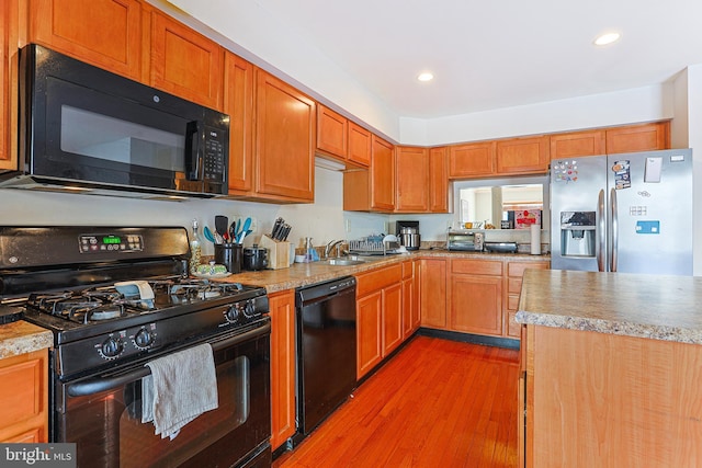 kitchen with sink, light hardwood / wood-style flooring, and black appliances