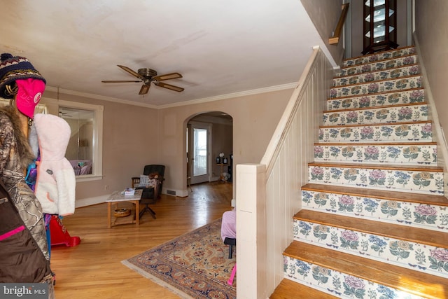 staircase with hardwood / wood-style flooring, ornamental molding, and ceiling fan