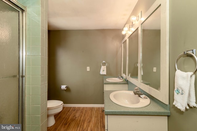 bathroom featuring hardwood / wood-style flooring, vanity, a shower with door, and toilet