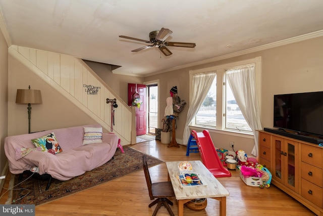 living room featuring ornamental molding, light hardwood / wood-style floors, and ceiling fan