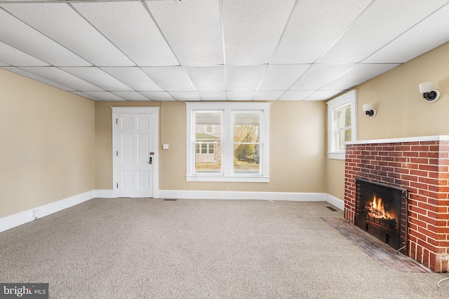 unfurnished living room featuring a brick fireplace, carpet flooring, and a paneled ceiling