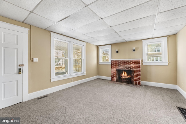 unfurnished living room with carpet, a drop ceiling, and a fireplace