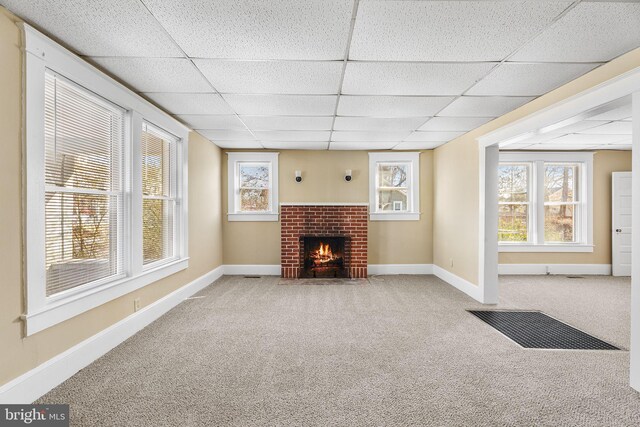 unfurnished living room featuring a fireplace, carpet floors, and a drop ceiling