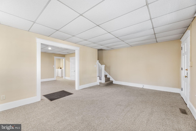 basement with light carpet and a paneled ceiling