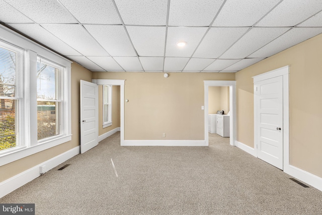 carpeted empty room featuring washer and clothes dryer and a paneled ceiling