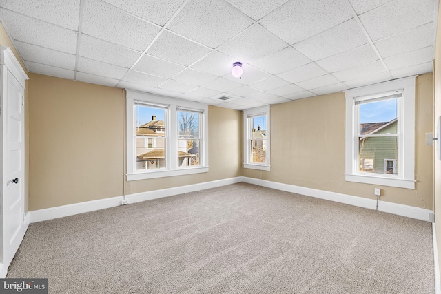 carpeted empty room with a drop ceiling and a healthy amount of sunlight