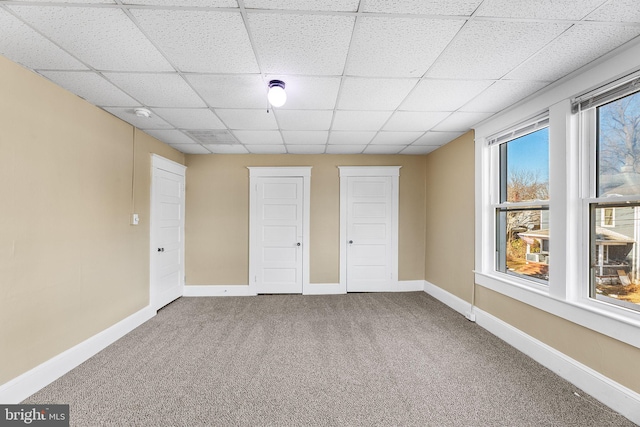 unfurnished bedroom with two closets, carpet floors, and a paneled ceiling