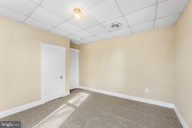 spare room featuring a paneled ceiling and carpet flooring