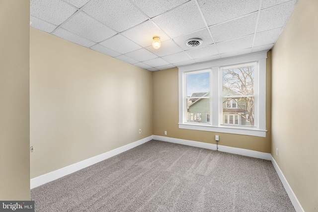 unfurnished room featuring carpet and a drop ceiling