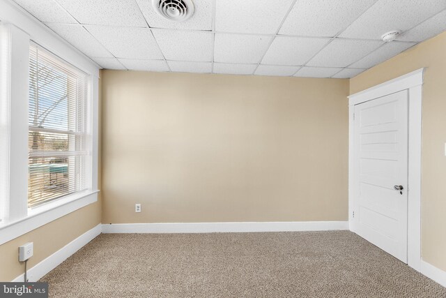 carpeted empty room with a drop ceiling