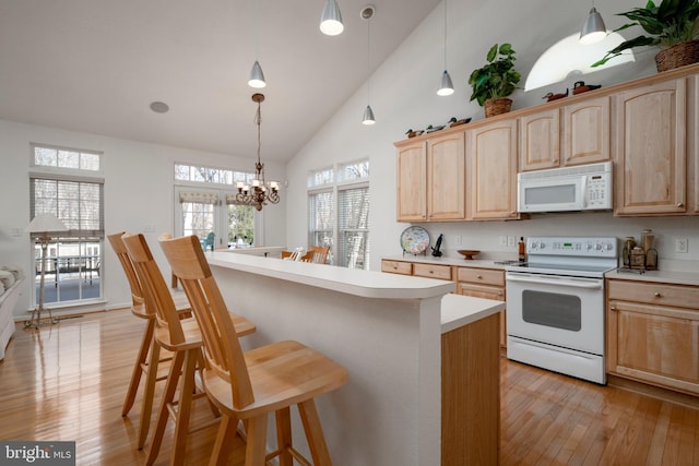 38015 E Chester Ln, Ocean View, DE 19970 - kitchen featuring white appliances, a breakfast bar area, light hardwood / wood-style floors, light brown cabinetry, and decorative light fixtures