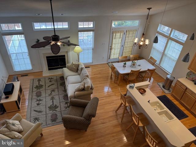 living room with light wood-type flooring and ceiling fan with notable chandelier