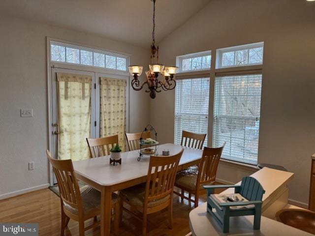 dining area with lofted ceiling, a chandelier, and light wood-type flooring