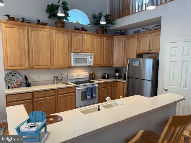 kitchen featuring sink, white appliances, a kitchen bar, and plenty of natural light