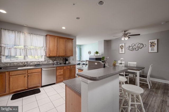 kitchen featuring sink, a breakfast bar, dishwasher, tasteful backsplash, and an island with sink