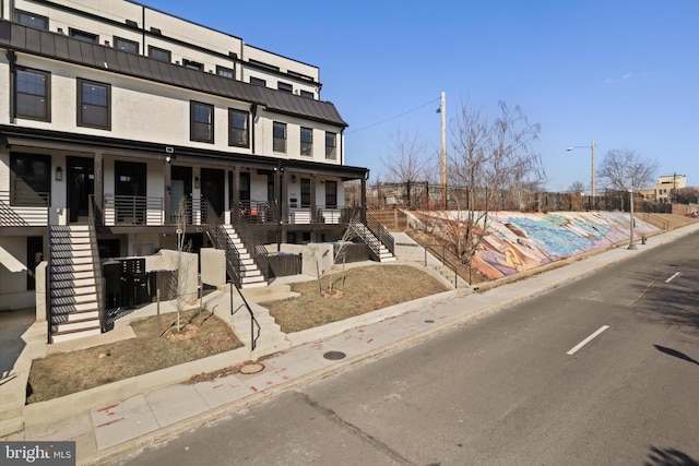 view of front facade with covered porch, stairway, metal roof, and a standing seam roof