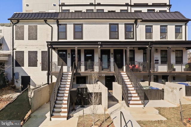 view of front of property featuring stairs, metal roof, brick siding, and a standing seam roof