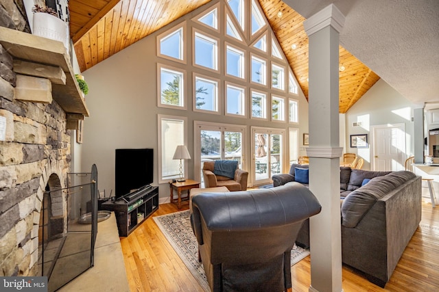 living room with wood ceiling, a fireplace, light wood-type flooring, and ornate columns