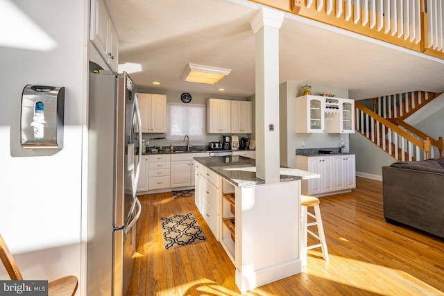 kitchen featuring white cabinetry, light wood-type flooring, a center island, and a breakfast bar