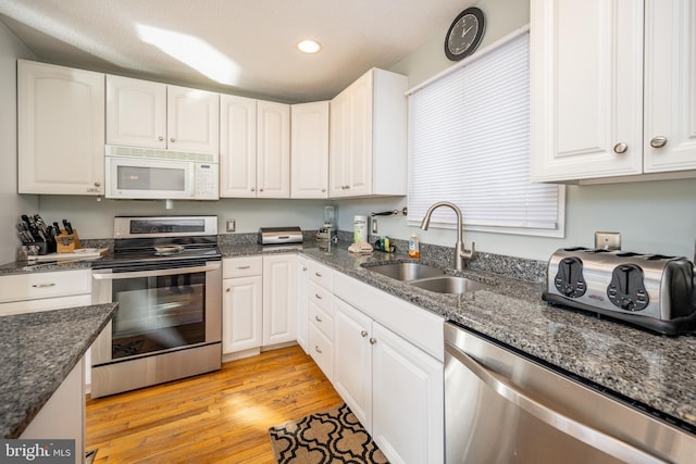 kitchen featuring white cabinetry, appliances with stainless steel finishes, sink, and light hardwood / wood-style flooring