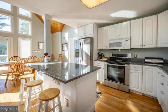 kitchen featuring stainless steel appliances, a breakfast bar, light wood-type flooring, and white cabinets