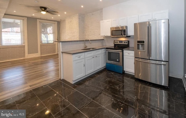 kitchen with sink, ceiling fan, appliances with stainless steel finishes, tasteful backsplash, and white cabinets