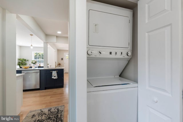 clothes washing area featuring stacked washer and dryer and light hardwood / wood-style floors