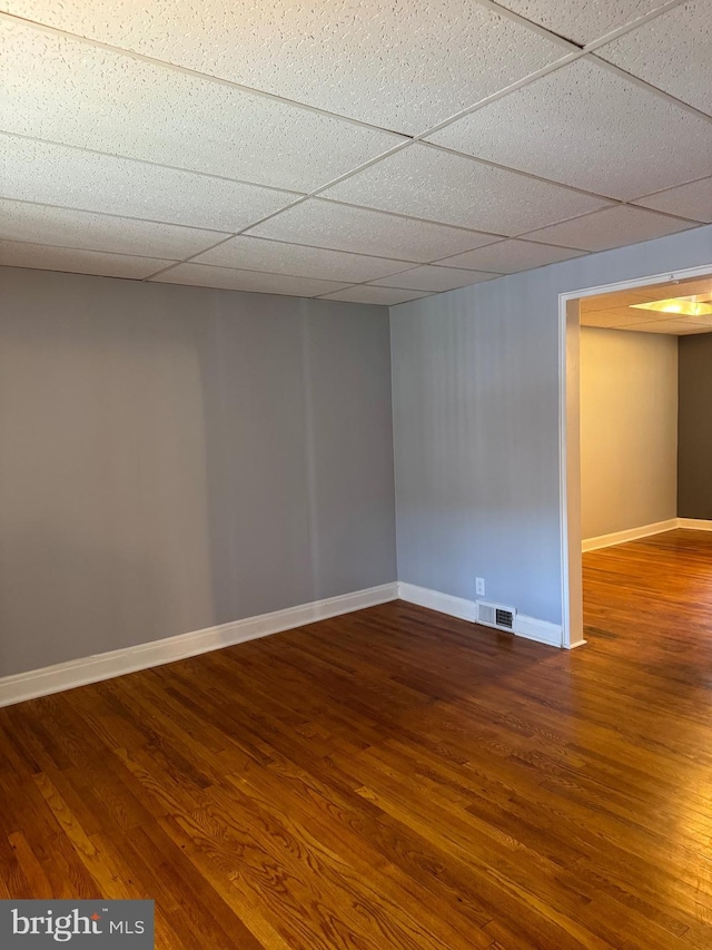 unfurnished room with hardwood / wood-style floors and a drop ceiling