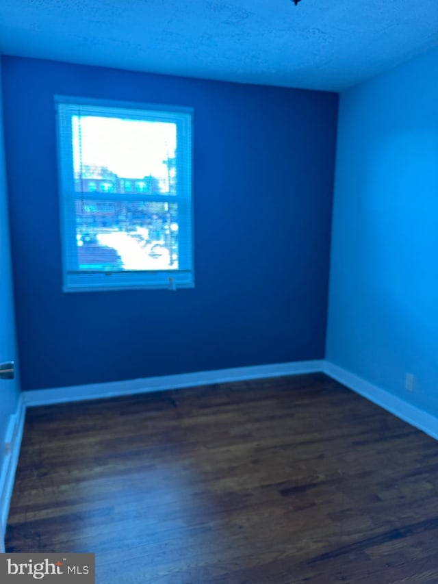 empty room featuring dark wood-type flooring and a textured ceiling