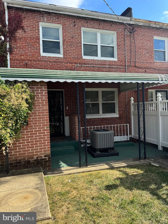 rear view of property featuring cooling unit and a yard