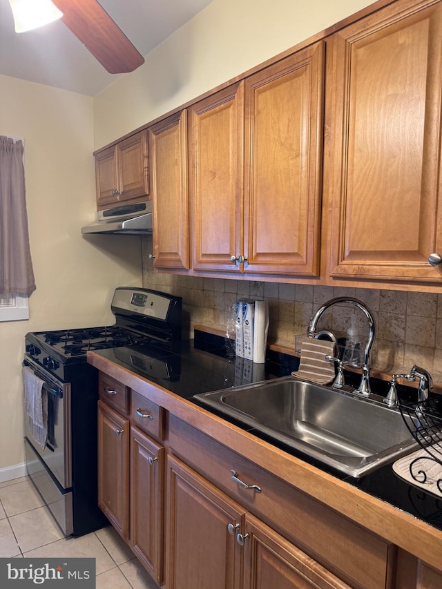 kitchen featuring sink, decorative backsplash, light tile patterned floors, and gas range