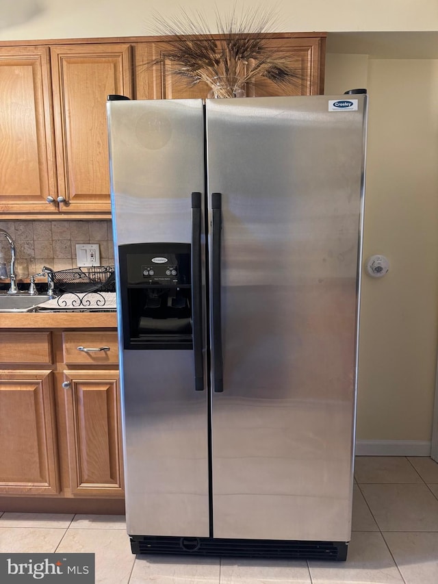 kitchen with sink, light tile patterned floors, tasteful backsplash, and stainless steel fridge